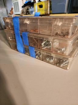 Three plastic boxes of screws and bolts.
