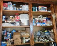 Cabinet contents including banners and vacuum cleaner on floor.