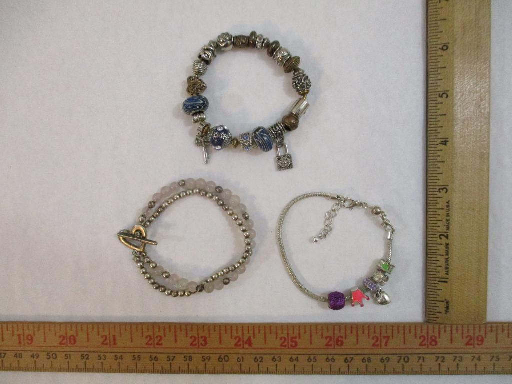 Three Silver Tone Bracelets including two-strand with beads, charms and more, 3 oz