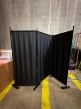 PORTABLE BLACK NYLON DIVIDER WALL ON WHEELS, TRI-FOLD, EACH PANEL 28" X 64"H, W/FRAME 69-1/2" H X