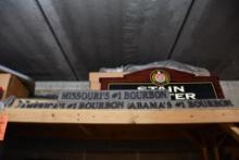 ASSORTED SIGNS ON TOP SHELF: STAIN CENTER, BOURBON, ISUZU, ETC.