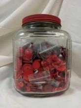 Clear glass Button jar filled with an assortment of Varying Styles and Shades of red buttons,