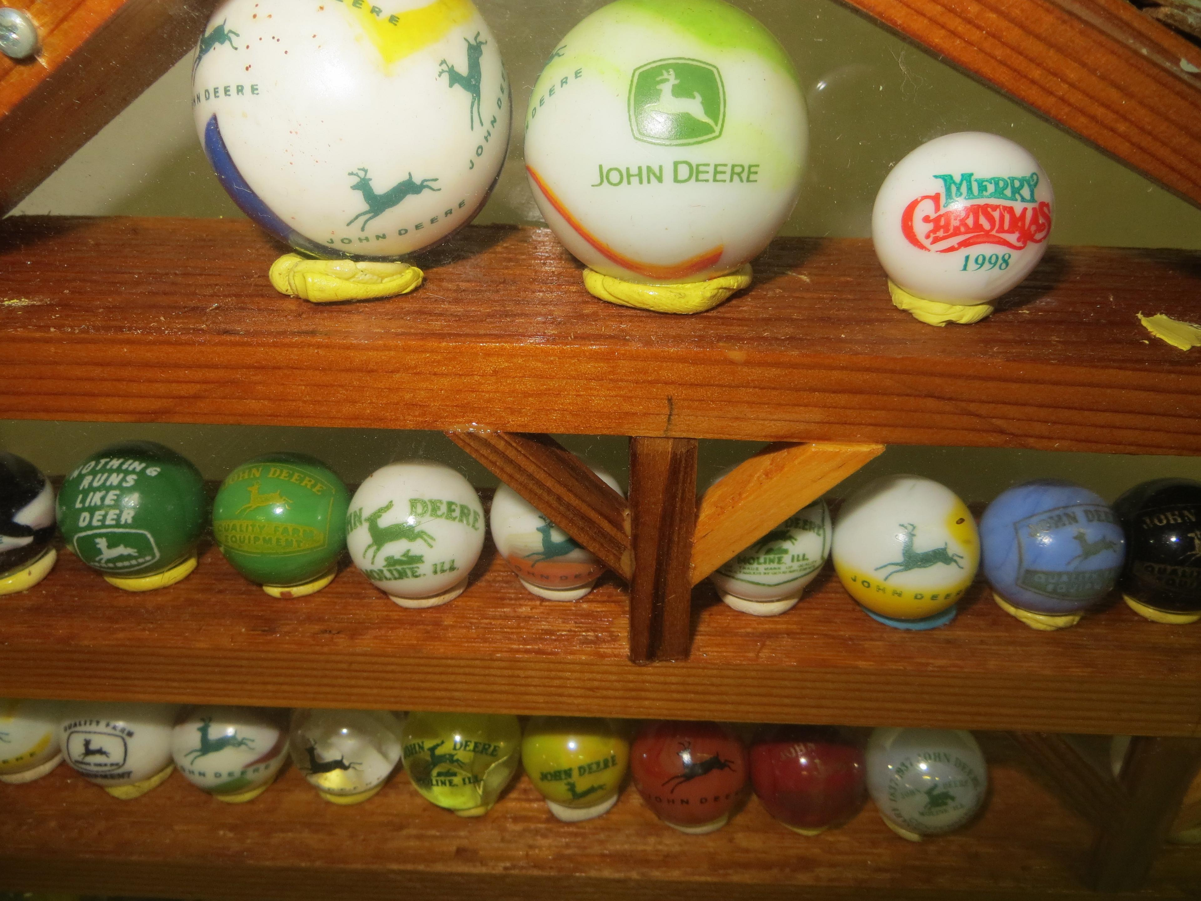 Large collection of John Deere marbles of all sizes in a barn display case