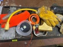 Black mat with contents on top. Which includes gloves, nuts, bolts, Small extension, cord, wire, and