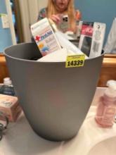 Wastebasket, full of first aid items, soap, comb, and more
