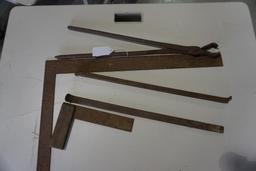 One framing square, small wood and metal square, blacksmith's tongs, and metal pry bar.