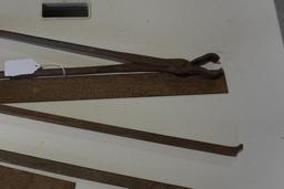 One framing square, small wood and metal square, blacksmith's tongs, and metal pry bar.