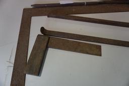 One framing square, small wood and metal square, blacksmith's tongs, and metal pry bar.
