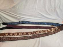 Three colorful cloth guitar straps and one leather strap.