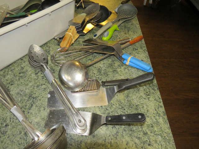 group of utensils including tongs, spatulas, stainless serving spoons, and other commercial service