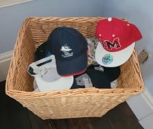 Wicker Basket full of Baseball Caps, some are new, some Trump Hats
