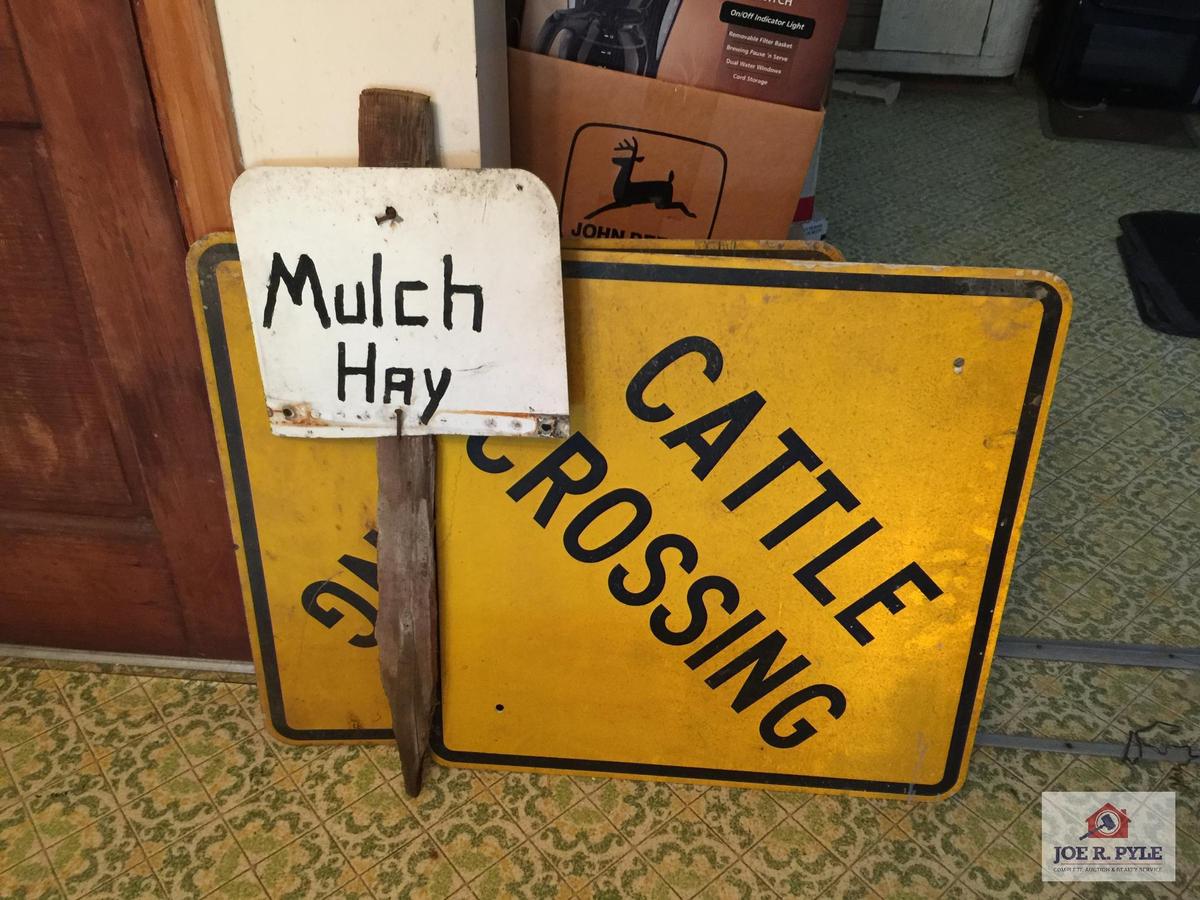 Two metal cattle crossing signs and mulch hay sign