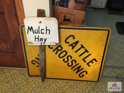 Two metal cattle crossing signs and mulch hay sign