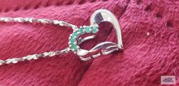 Silver colored heart-shaped pendant with green gemstones, marked 925, on silver colored twist