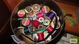 Tin of wooden spooled thread. Measuring tape. Sewing scissors. Buttons.