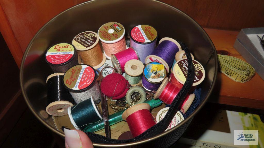 Tin of wooden spooled thread. Measuring tape. Sewing scissors. Buttons.