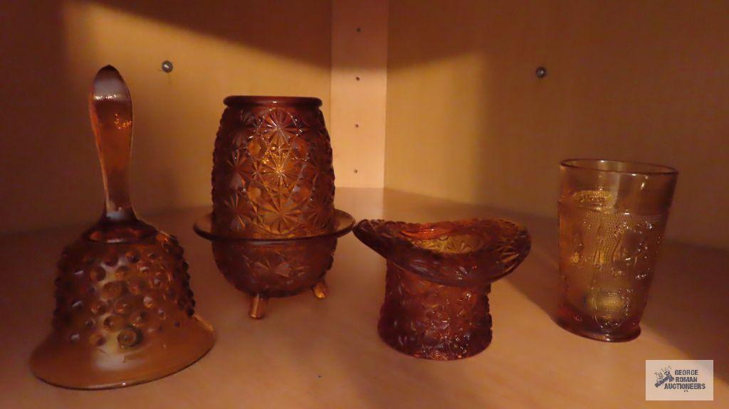 Amber colored glass bell, top hat, candle holder, and cup