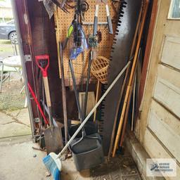 Lot of antique saw parts, yard and garden tools and etc on pegboard and on floor