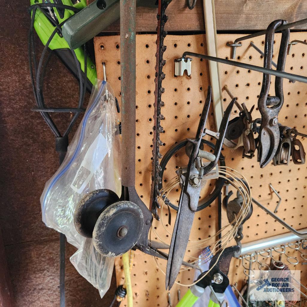 Lot of antique saw parts, yard and garden tools and etc on pegboard and on floor