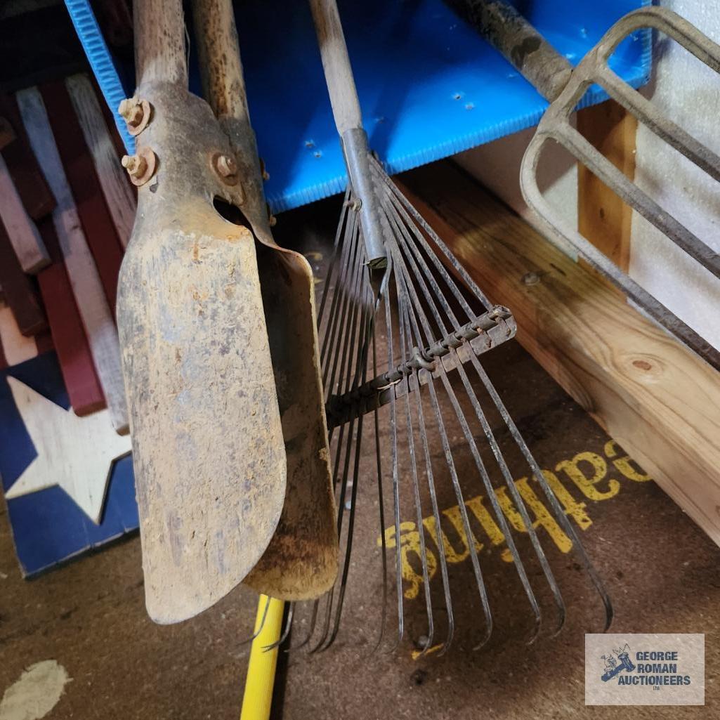 Lot of antique pitchforks, yard and garden tools, and corrugated plastic bin