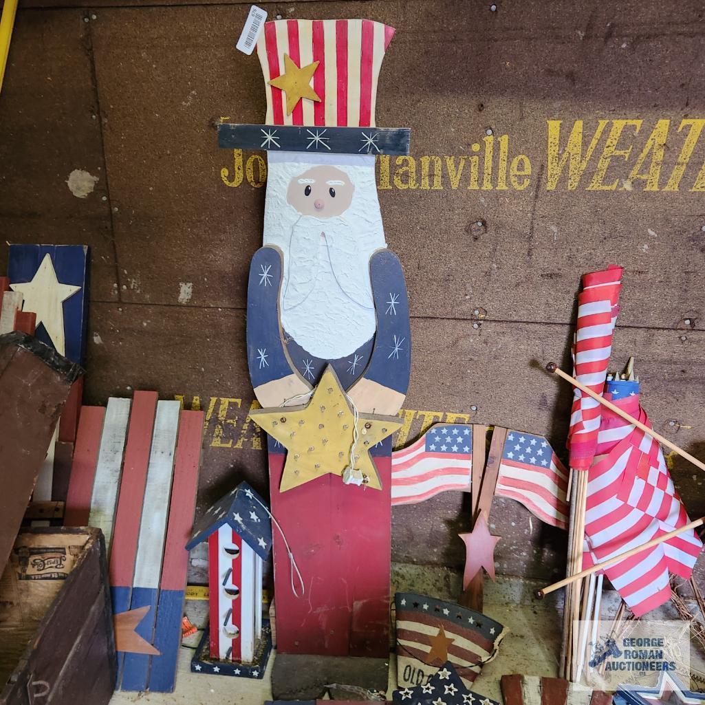 Lot of patriotic decorations including plastic flag, wooden flags, bird houses and Uncle Sam