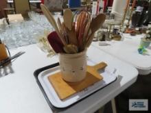 Metal trays, kitchen utensils in crock, and wooden cutting board