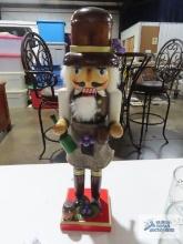 Wooden nutcracker holding wine and grapes, approximately 15 inches tall.
