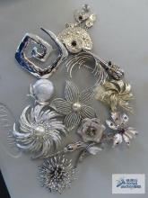 Variety of silver colored pins, including Sarah Covington and Lisner