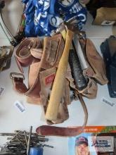 WE tool belt with assorted tools, including hammer, square, tape measure, rasp, etc.