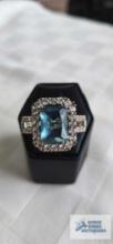 Silver colored ring with large pale blue stone and surrounding clear gemstones, marked 925, 7.5 G,