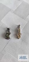 Silver colored pendant with pale green stone and silver colored pendant with yellow stones. Both