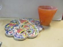 Floral Ceramic Round Trivet and Orange Art Glass Cup.