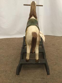 Antique wooden rocking horse with colorful painted adornments and dark base