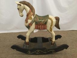 Antique wooden rocking horse with colorful painted adornments and dark base