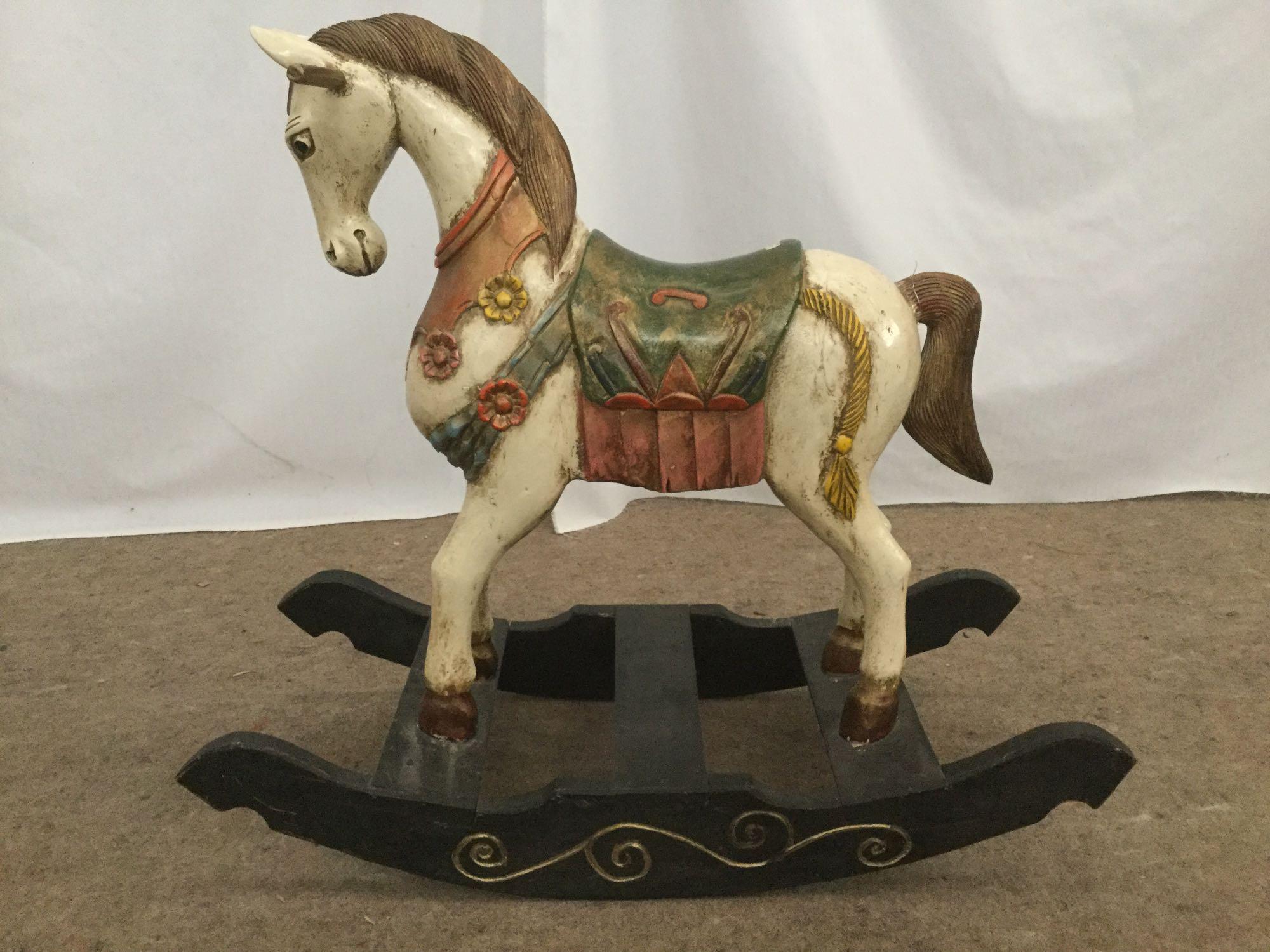 Antique wooden rocking horse with colorful painted adornments and dark base