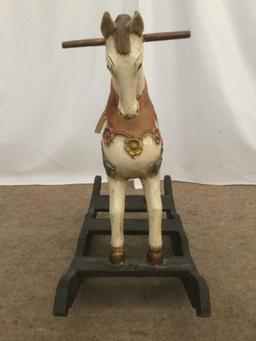 Antique wooden rocking horse with colorful painted adornments and dark base