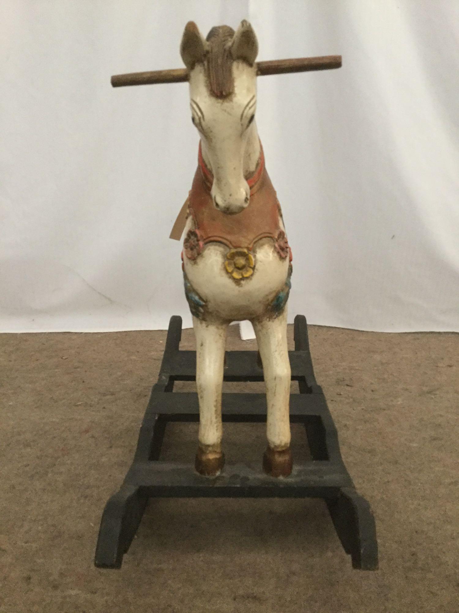 Antique wooden rocking horse with colorful painted adornments and dark base