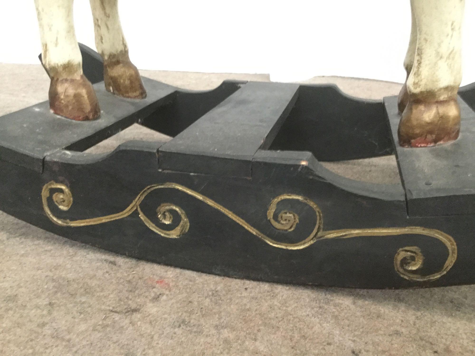 Antique wooden rocking horse with colorful painted adornments and dark base