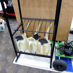 Automotive fluid jug organizer rack has space for twelve jugs - comes with 6 six quart dispenser