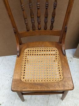 Nice sturdy wooden chair with ornate carving in the back, and a wicker seat. The chair is in overall