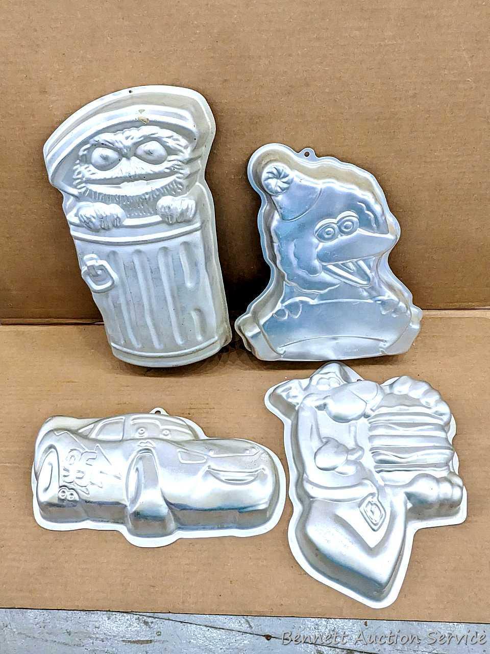 Four Wilton character cake pans including Oscar the Grouch, Cars, Scooby Doo, and Big Bird. Largest