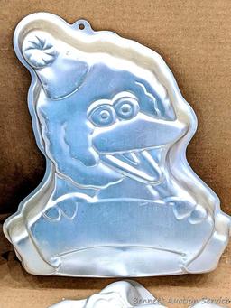 Four Wilton character cake pans including Oscar the Grouch, Cars, Scooby Doo, and Big Bird. Largest