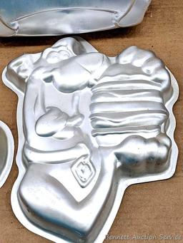 Four Wilton character cake pans including Oscar the Grouch, Cars, Scooby Doo, and Big Bird. Largest