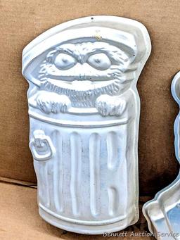 Four Wilton character cake pans including Oscar the Grouch, Cars, Scooby Doo, and Big Bird. Largest