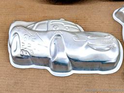 Four Wilton character cake pans including Oscar the Grouch, Cars, Scooby Doo, and Big Bird. Largest