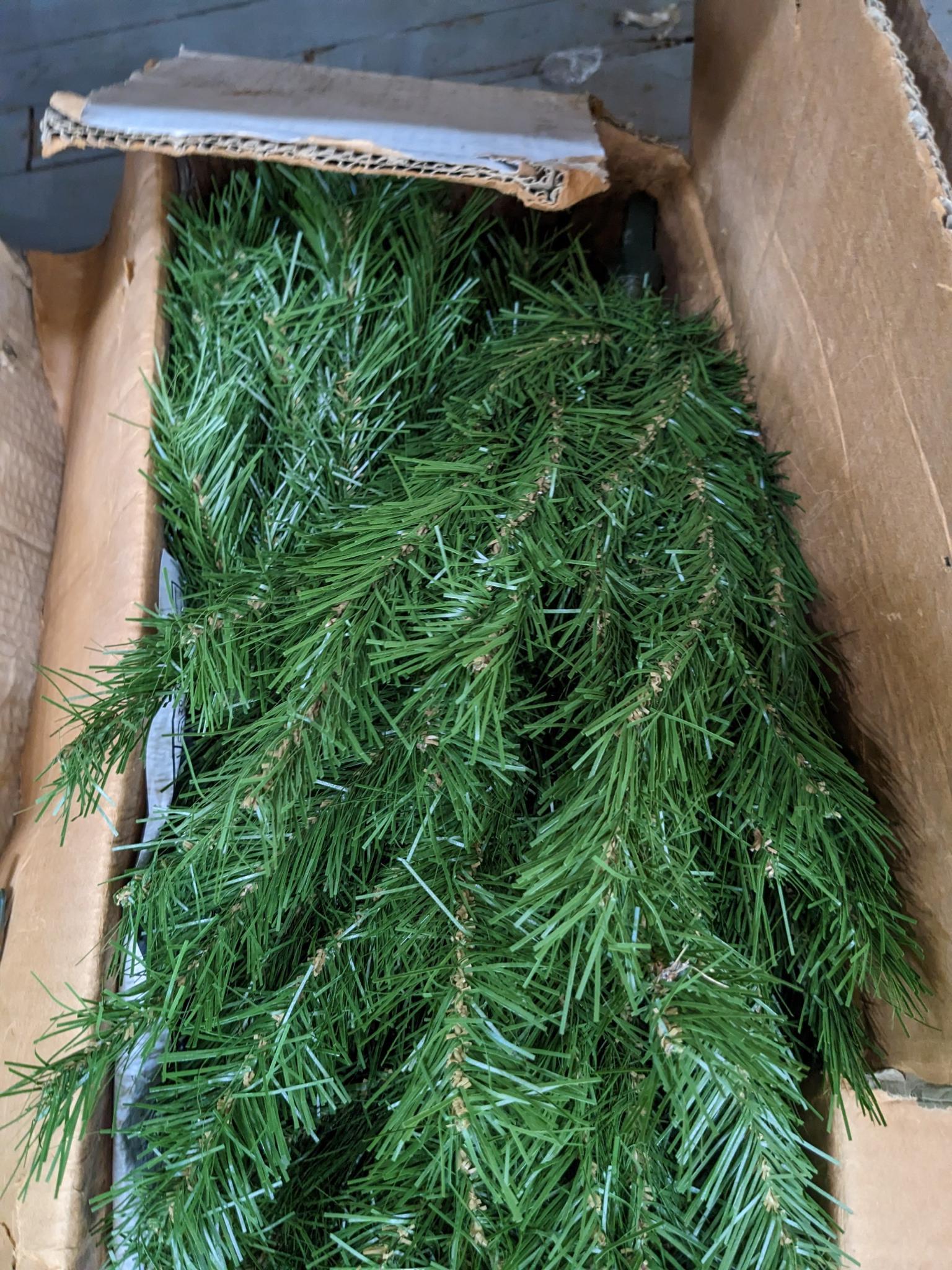 Two artificial Christmas trees, one is strung with lights and the other isn't, unchecked if