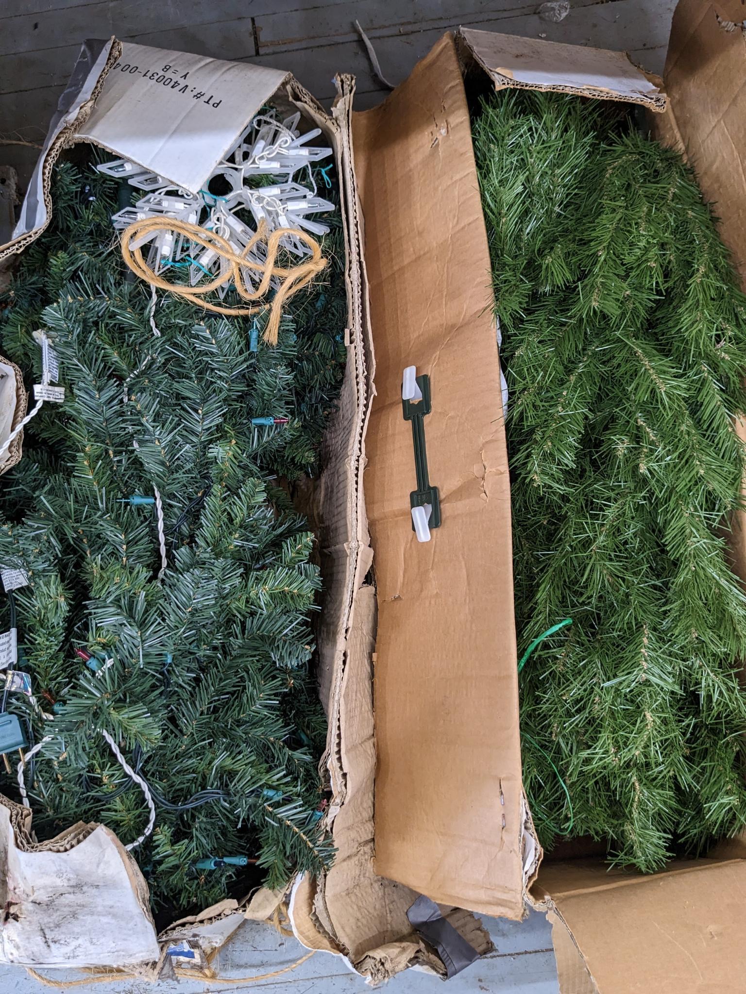 Two artificial Christmas trees, one is strung with lights and the other isn't, unchecked if