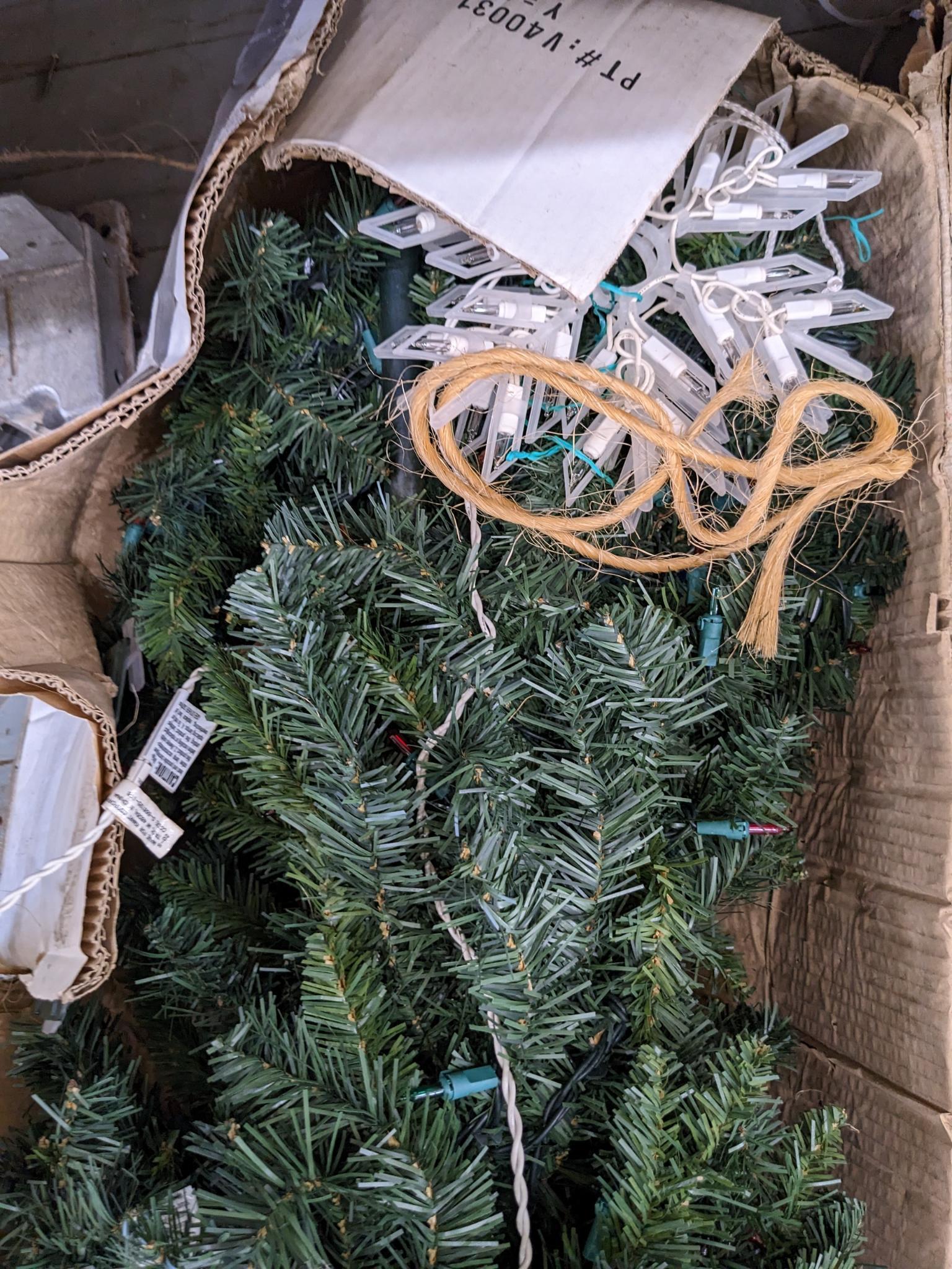Two artificial Christmas trees, one is strung with lights and the other isn't, unchecked if