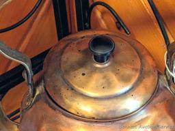Copper colored tea kettle with black handle. Lid doesn't seat easily, measures 9-1/2" over handle.