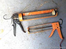 Pair of orange caulking guns. The larger gun is a heavy duty one and measures 17" over the handle.